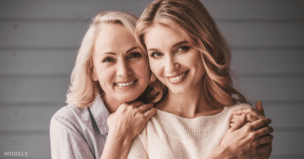 An older and younger woman smiling at the camera (models)