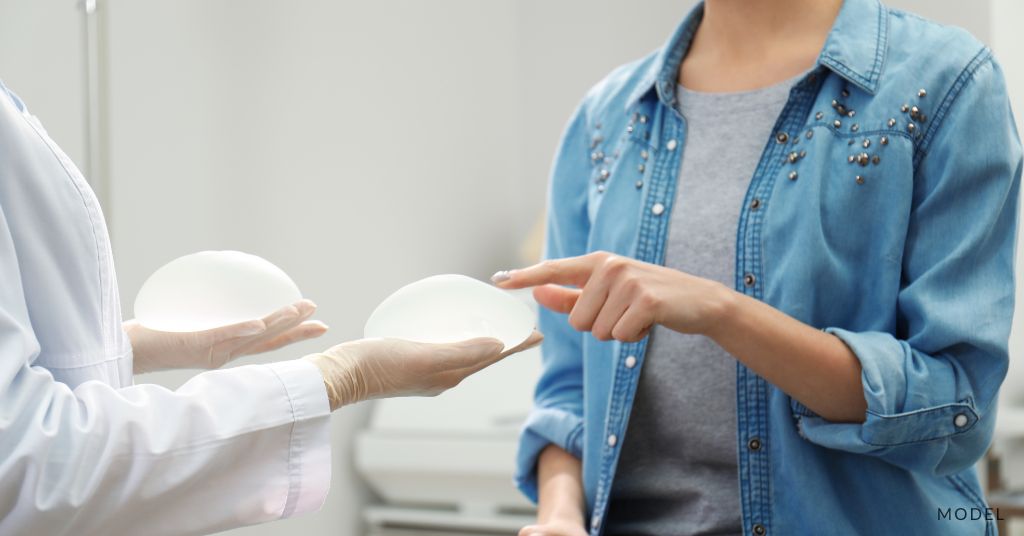 Medical professional holding out breast implants for woman to examine. (models)