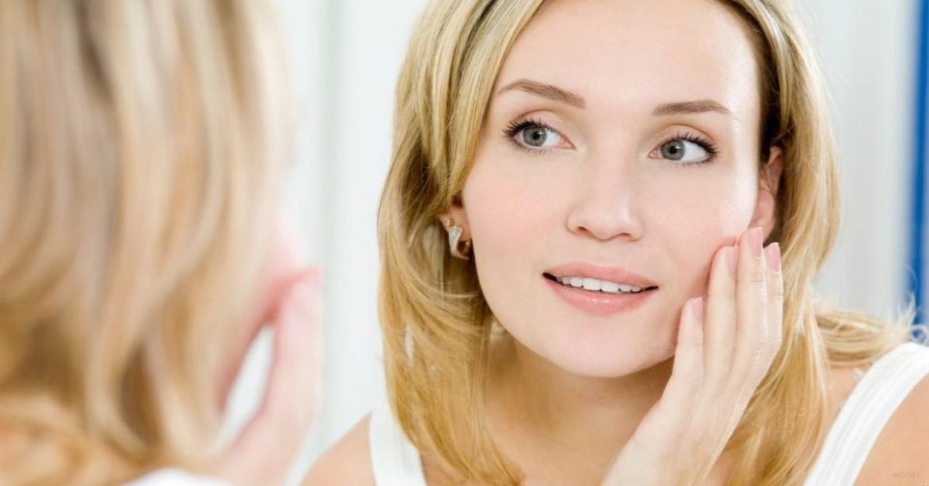 A person looking at their face in the mirror (model)