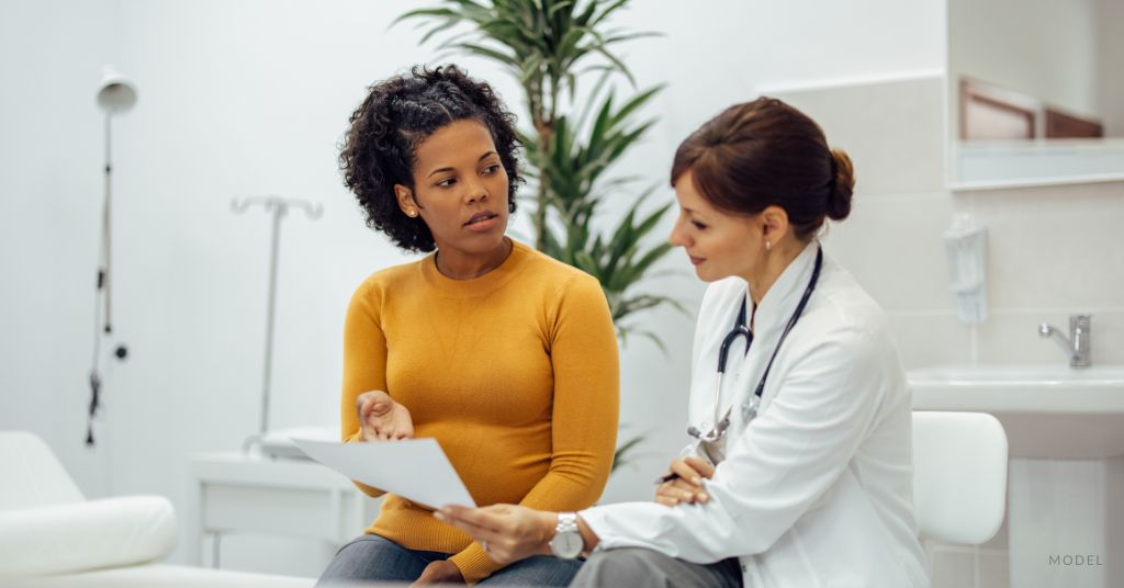 A woman speaks with her doctor in doctor's office. (Models)