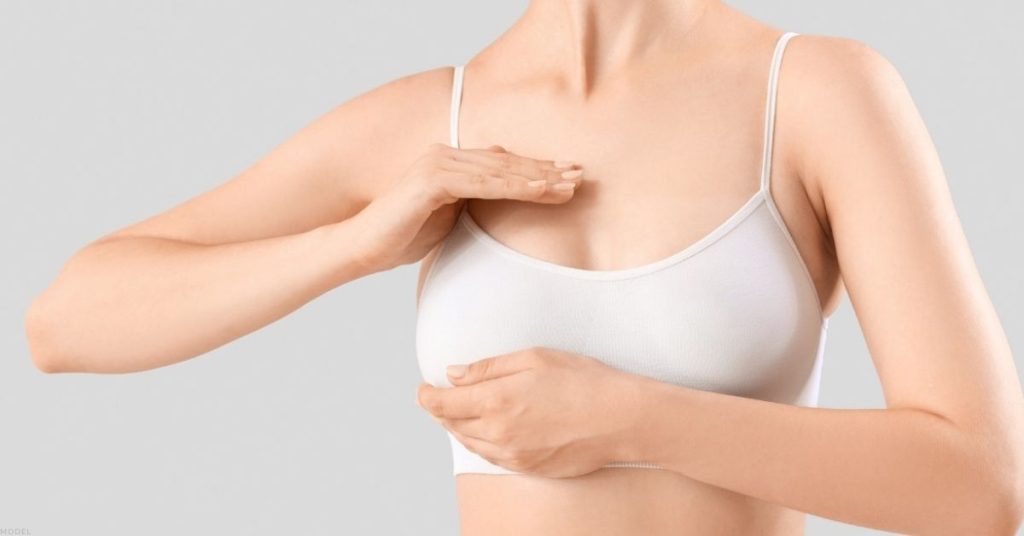 a person in a white bra top is touching their chest (model)