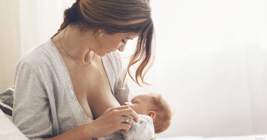 Young woman breastfeeding her baby on a bed (models)