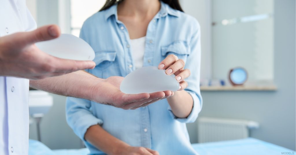 Woman selecting breast implants during a consultation at a medical office (models)